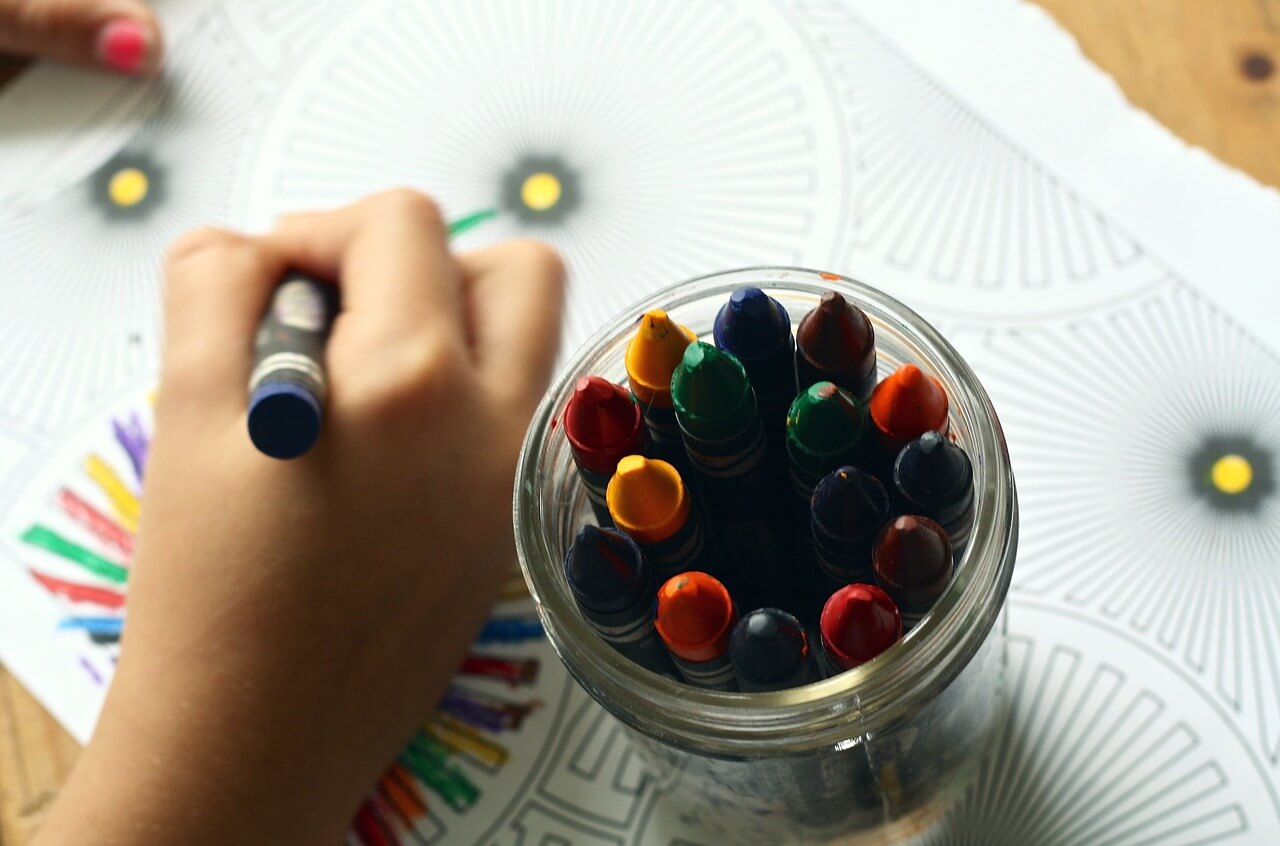 Criança pintando desenho de recreação com giz de cera